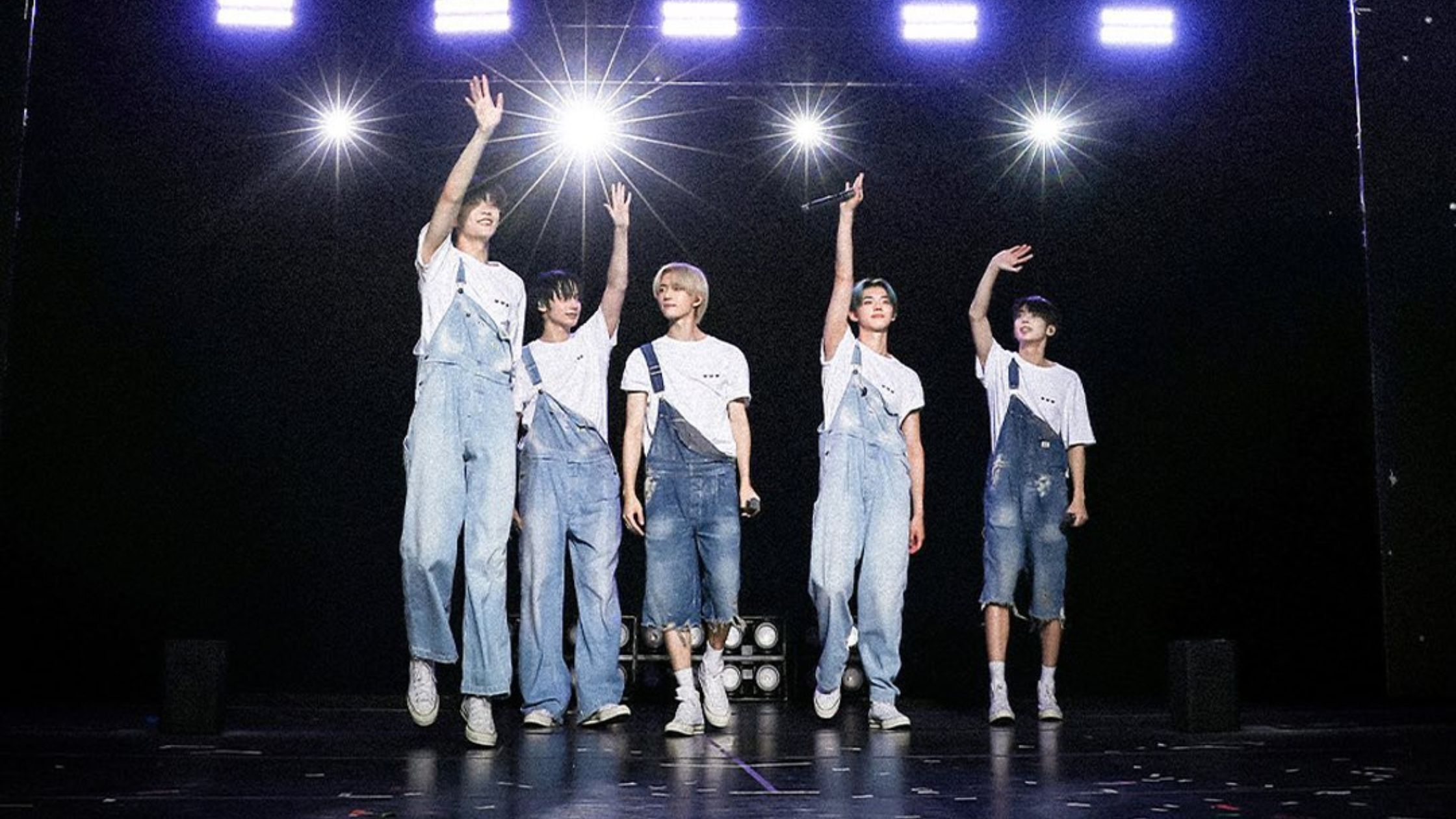 The singers of TXT performing on a stage. 