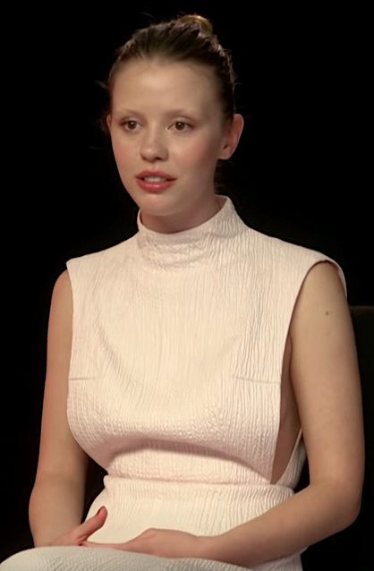 Mia wearing white dress in an interview.