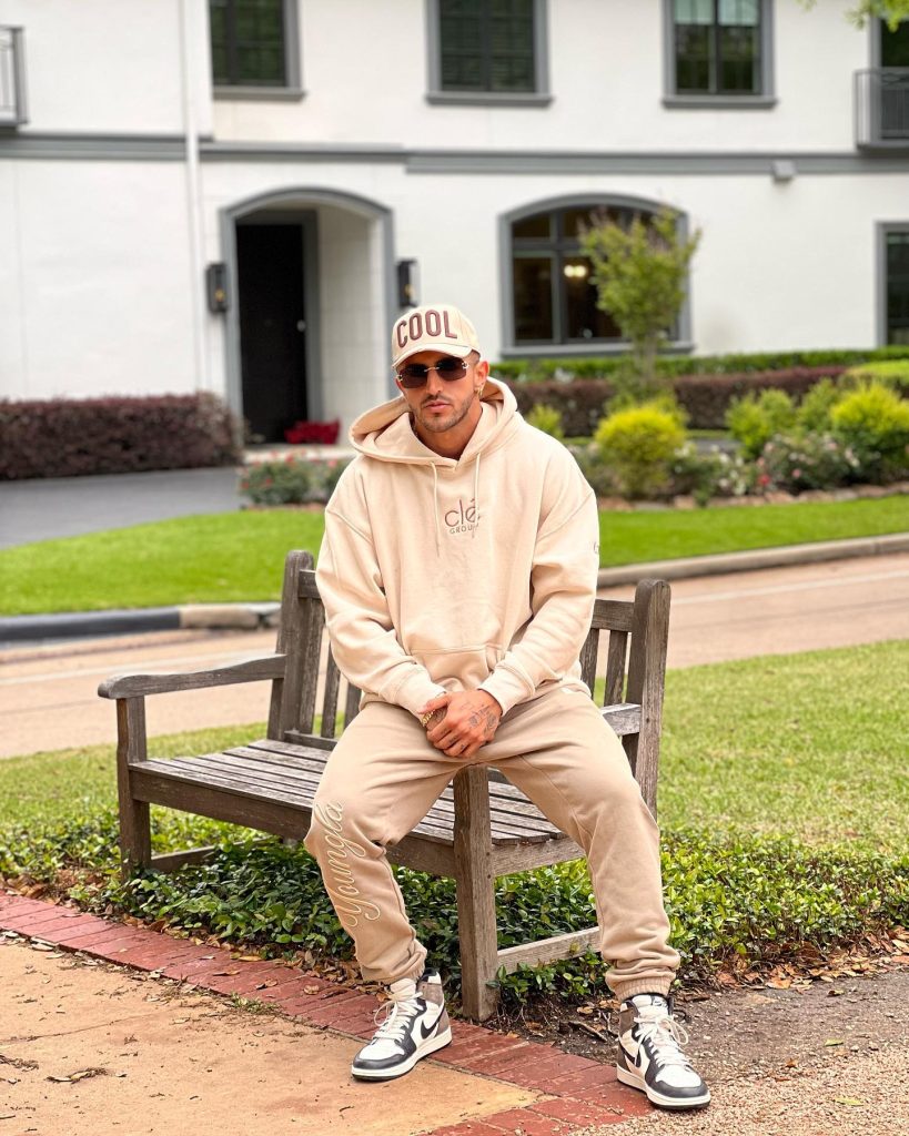 Aisan sitting on a bench wearing beige colored clothes.