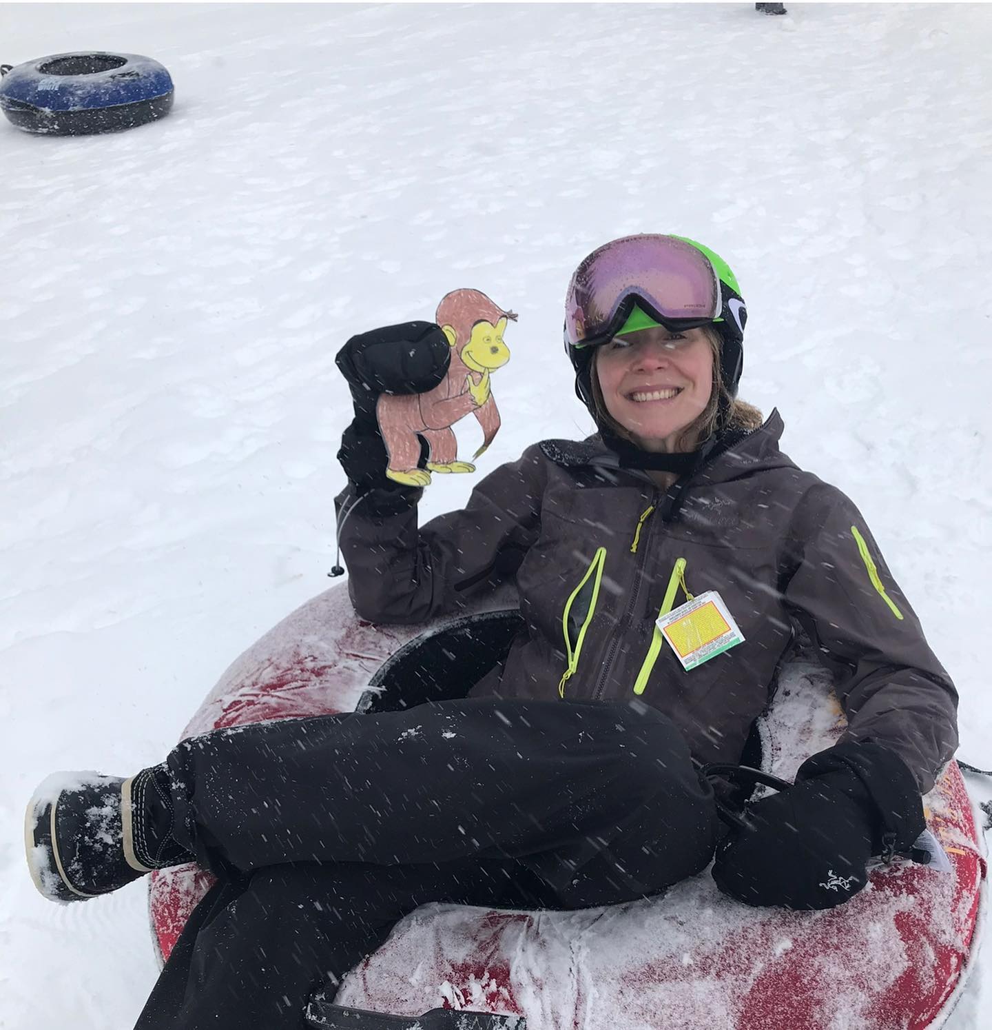 Sarah holding a monkey puppet and sitting in snow.